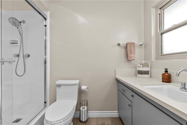 full bath with toilet, wood finished floors, a shower stall, baseboards, and vanity