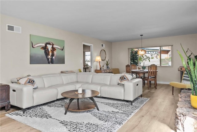 living area with visible vents, baseboards, and light wood-style flooring