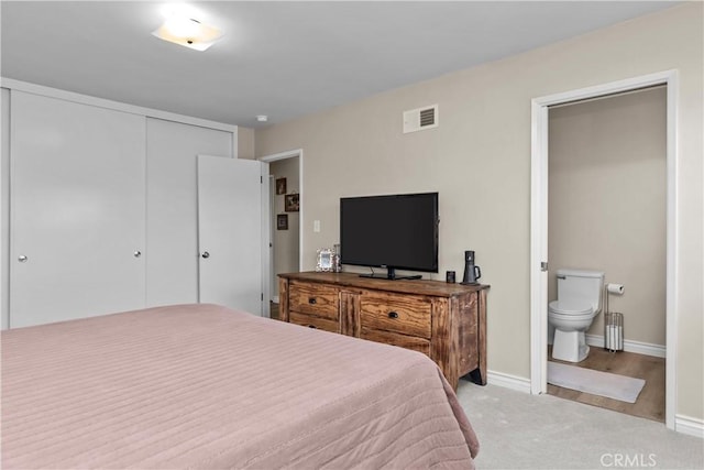 bedroom with visible vents, connected bathroom, baseboards, light colored carpet, and a closet