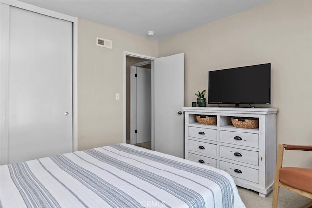 bedroom featuring visible vents, light carpet, and a closet