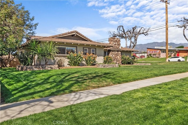 single story home with stucco siding, a chimney, and a front yard