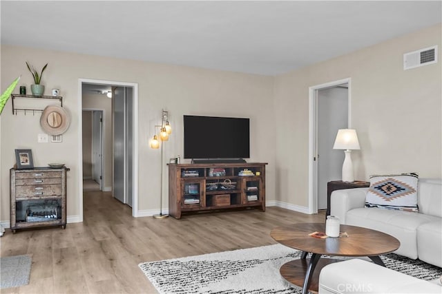 living room featuring baseboards, visible vents, and light wood finished floors