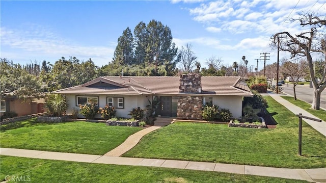 ranch-style house with a chimney, stucco siding, a tile roof, and a front yard