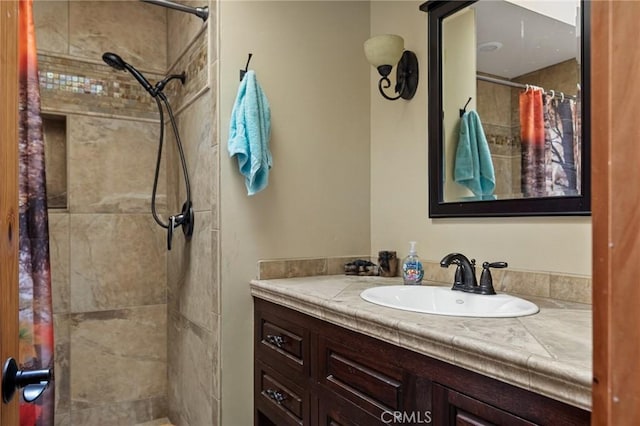 full bathroom featuring tiled shower and vanity