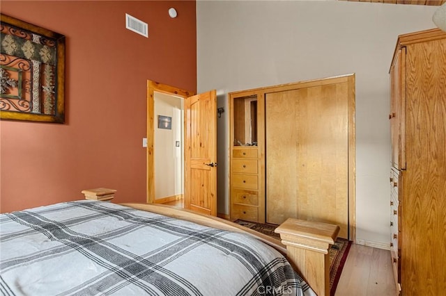 bedroom with a high ceiling, wood finished floors, and visible vents