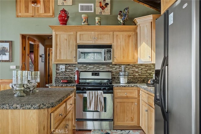 kitchen with appliances with stainless steel finishes, light brown cabinets, visible vents, and tasteful backsplash