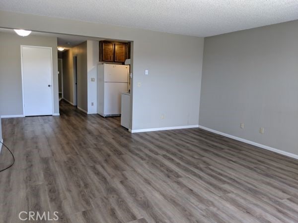 unfurnished living room featuring dark wood-style floors, a textured ceiling, and baseboards