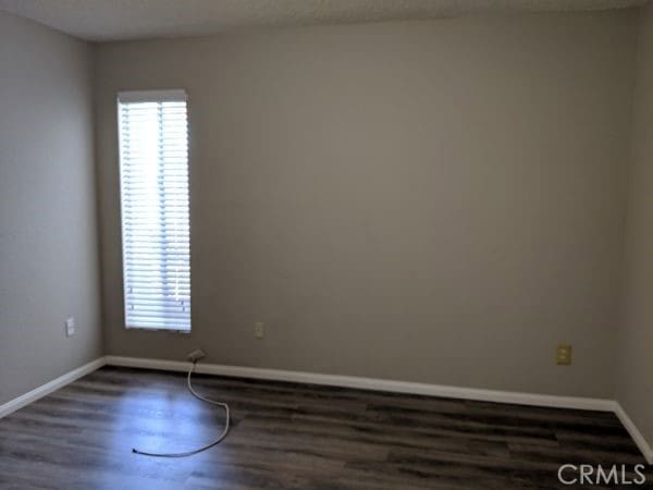 spare room featuring wood finished floors and baseboards