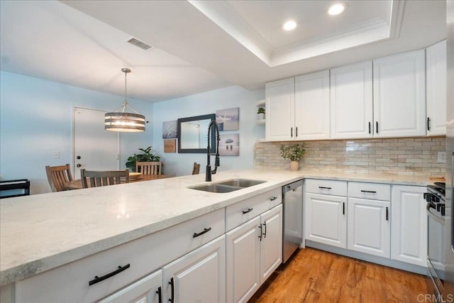 kitchen featuring tasteful backsplash, visible vents, a raised ceiling, dishwasher, and a sink