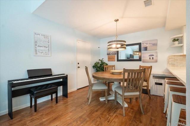 dining room featuring visible vents, baseboards, and wood finished floors