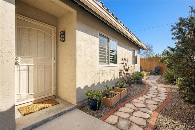 doorway to property featuring a patio area, fence, and stucco siding