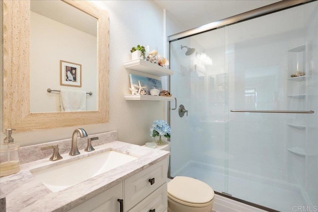 bathroom with a stall shower, vanity, and toilet