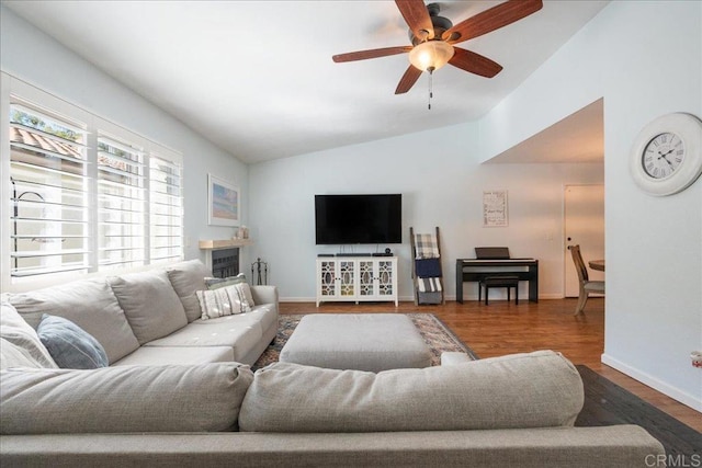 living room featuring a ceiling fan, lofted ceiling, baseboards, and wood finished floors