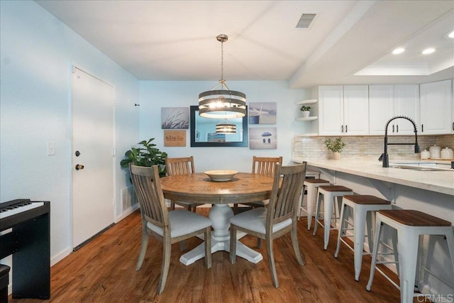 dining room featuring recessed lighting, wood finished floors, visible vents, baseboards, and a raised ceiling