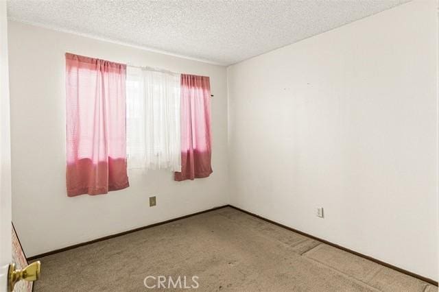 carpeted spare room featuring a textured ceiling and baseboards