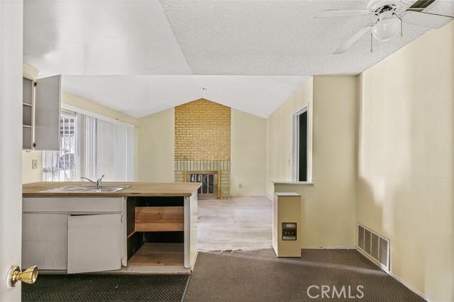 kitchen with visible vents, vaulted ceiling, carpet floors, a fireplace, and a sink