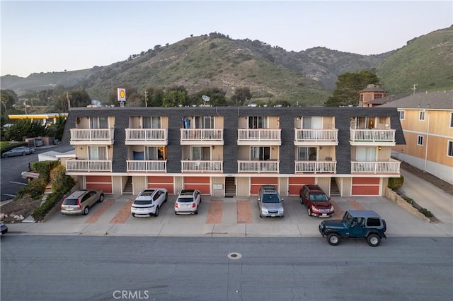 view of building exterior with uncovered parking and a mountain view