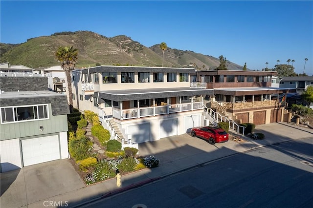 view of front of house with an attached garage, stairway, a mountain view, and concrete driveway