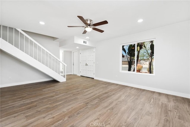 unfurnished living room featuring recessed lighting, stairs, baseboards, and wood finished floors