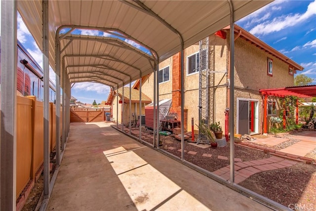 exterior space featuring a detached carport, fence, and stucco siding