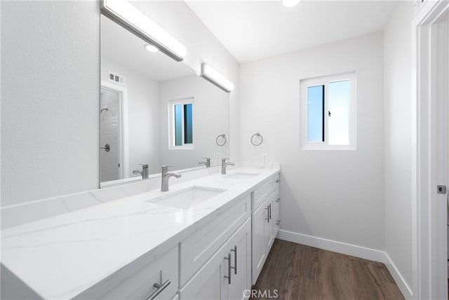 full bathroom featuring visible vents, wood finished floors, baseboards, and a sink