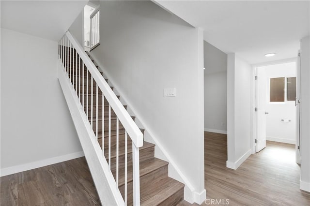 stairs featuring wood finished floors and baseboards