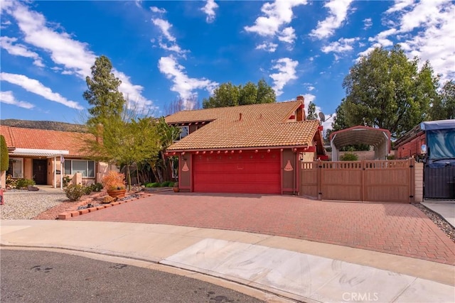 view of front of property with a tiled roof, decorative driveway, a garage, and a gate