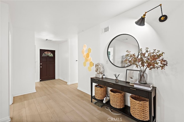 foyer featuring light wood-type flooring, visible vents, and baseboards
