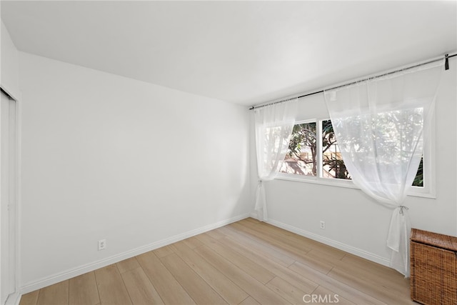 unfurnished room featuring light wood-type flooring and baseboards