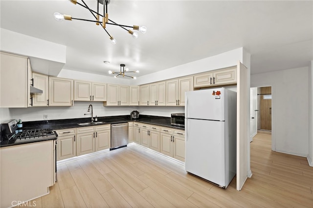 kitchen featuring dark countertops, stainless steel appliances, light wood-type flooring, and a sink