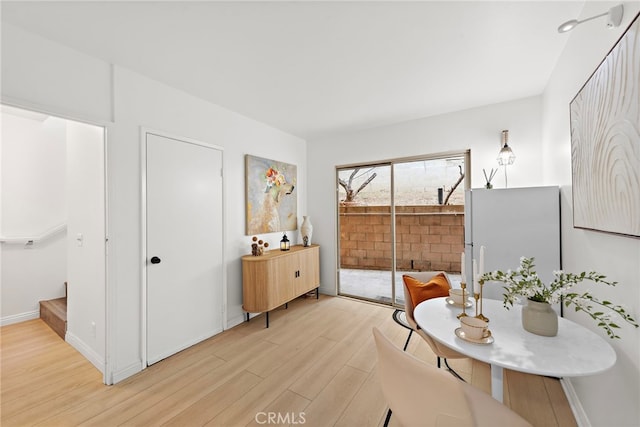 sitting room featuring light wood-style floors, baseboards, and stairway