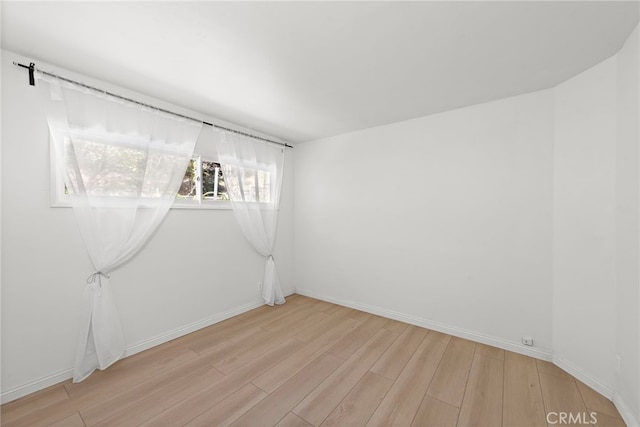 spare room featuring baseboards and light wood-style floors