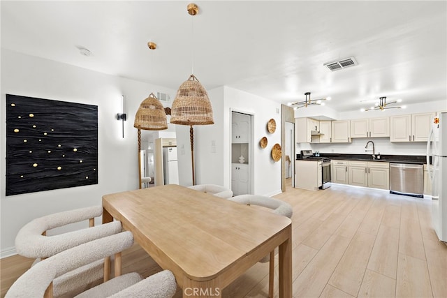 dining area featuring light wood-type flooring, visible vents, and baseboards