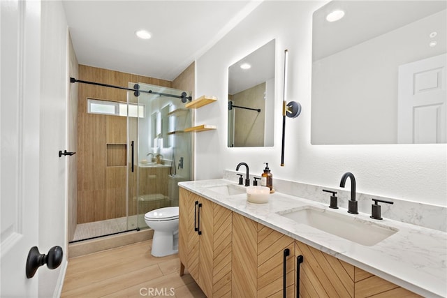 full bathroom featuring a sink, a shower stall, toilet, and double vanity
