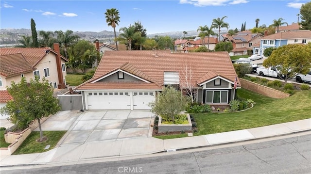 view of front of house featuring an attached garage, a front yard, fence, driveway, and a tiled roof