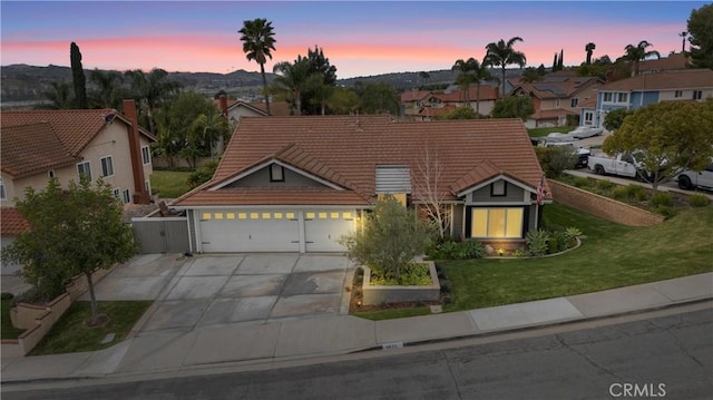 view of front of property with driveway, a garage, a tile roof, fence, and a front lawn