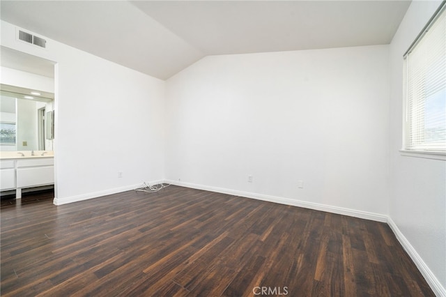 unfurnished bedroom featuring dark wood-style floors, lofted ceiling, visible vents, and multiple windows