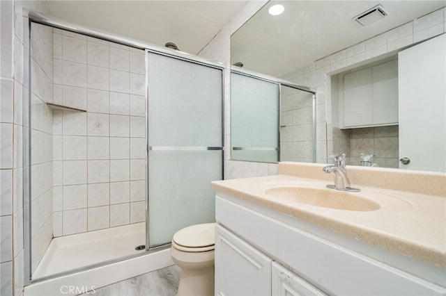 bathroom featuring toilet, a stall shower, visible vents, and vanity