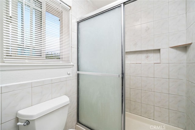 bathroom featuring a stall shower, tile walls, and toilet