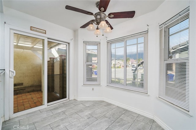 unfurnished sunroom featuring a ceiling fan