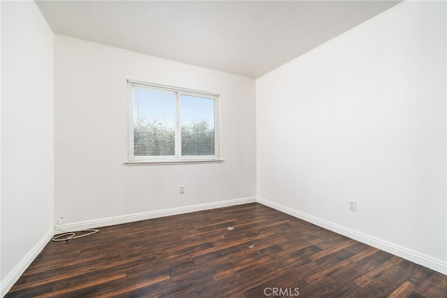 spare room with dark wood-style flooring and baseboards