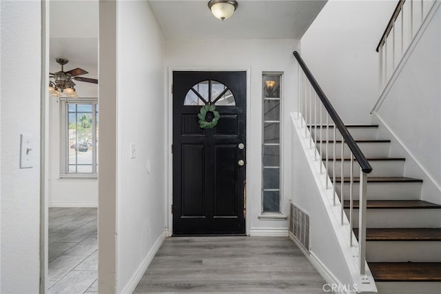 entrance foyer featuring visible vents, stairway, baseboards, and wood finished floors