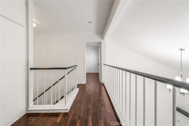 hallway with dark wood-style flooring, baseboards, and an upstairs landing