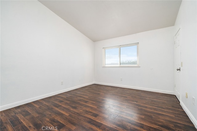 spare room with lofted ceiling, dark wood-style flooring, and baseboards