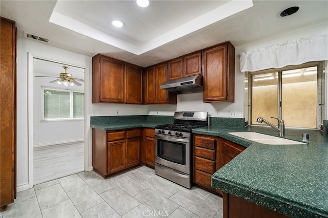 kitchen with under cabinet range hood, a sink, visible vents, gas stove, and a raised ceiling