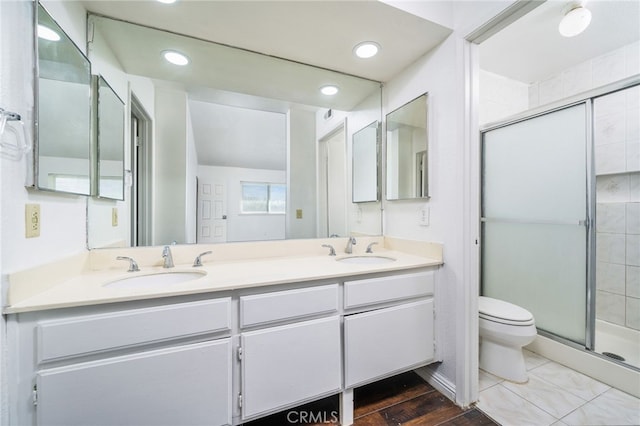 bathroom with a stall shower, a sink, toilet, and double vanity