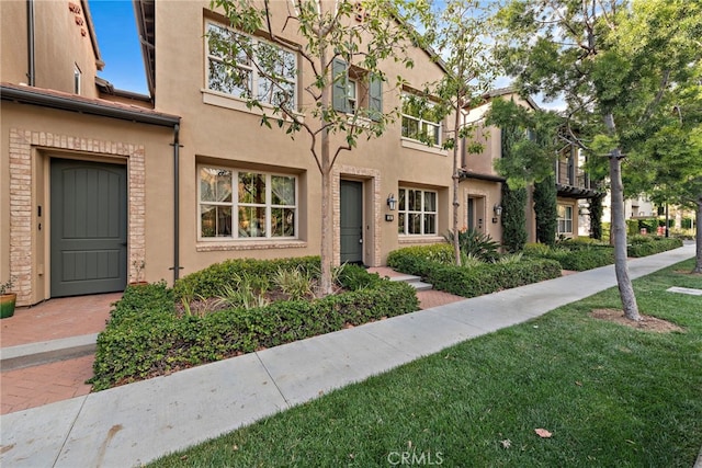 multi unit property featuring stucco siding and a front yard