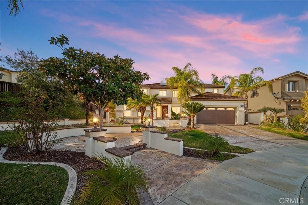 mediterranean / spanish-style home featuring a garage, driveway, and stucco siding