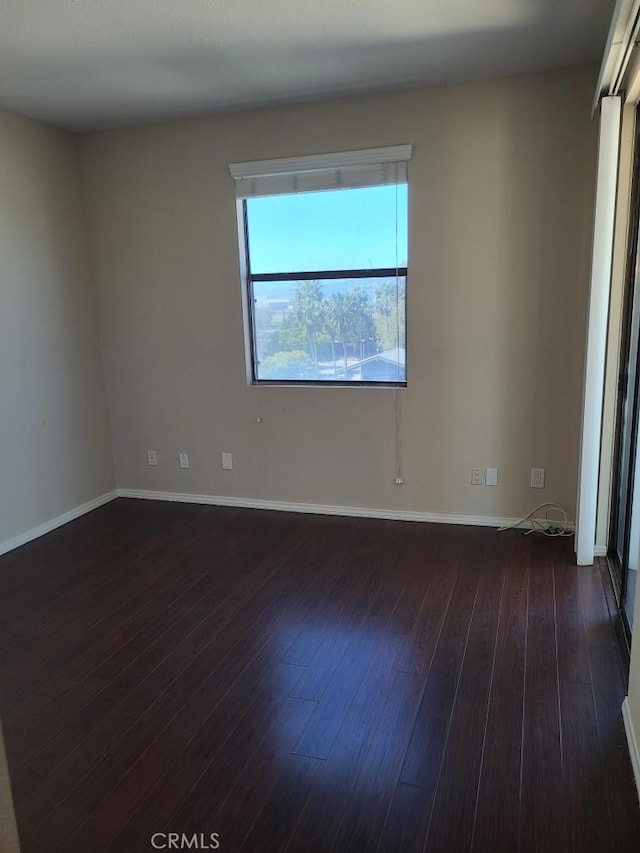 empty room featuring dark wood-style floors and baseboards