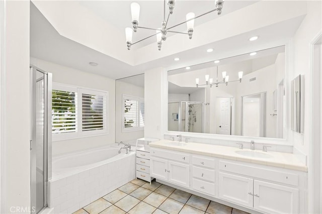 bathroom featuring double vanity, a sink, a shower stall, a chandelier, and a bath